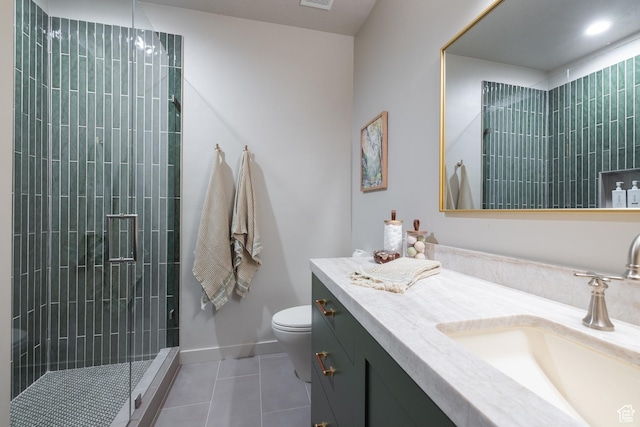 full bath featuring tile patterned flooring, a tile shower, toilet, vanity, and baseboards
