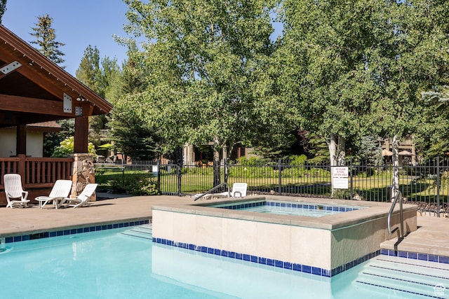 community pool with a hot tub and fence
