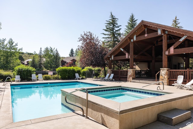 community pool featuring a hot tub, fence, and a patio area