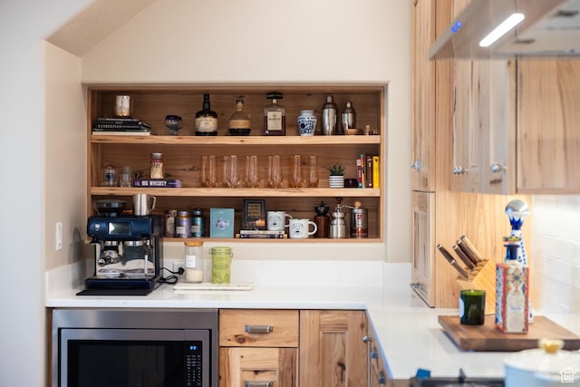bar featuring stainless steel microwave and under cabinet range hood