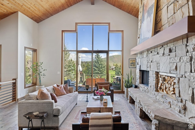 living room featuring high vaulted ceiling, a fireplace, wood finished floors, wooden ceiling, and a mountain view