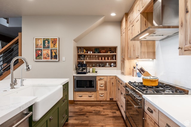 kitchen with appliances with stainless steel finishes, wall chimney exhaust hood, green cabinetry, a sink, and recessed lighting