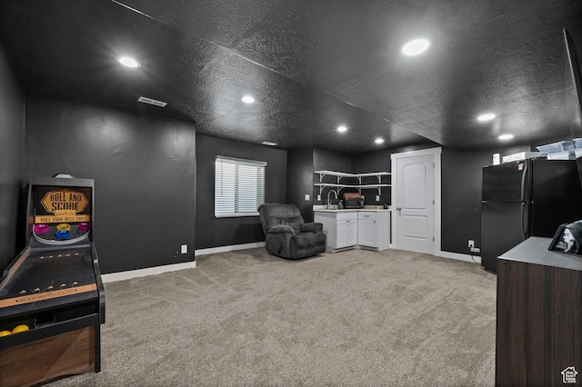 sitting room featuring light carpet, baseboards, recessed lighting, and a textured ceiling