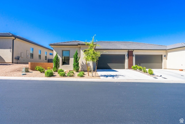 view of front of property with concrete driveway, an attached garage, and stucco siding
