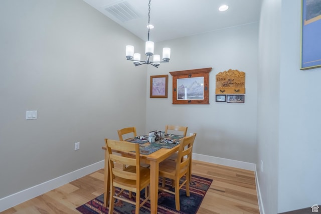 dining room with a chandelier, light wood finished floors, and baseboards