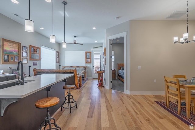 kitchen with light wood-style flooring, a chandelier, a kitchen breakfast bar, recessed lighting, and light countertops
