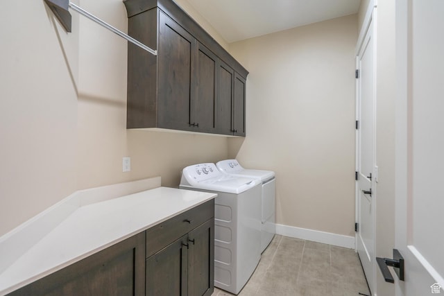 clothes washing area with cabinet space, washing machine and clothes dryer, baseboards, and light tile patterned floors