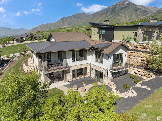 732 S Nebo Cir, Woodland Hills, UT 84653 - back of house with a balcony, stone siding, a patio area, a mountain view, and metal roof