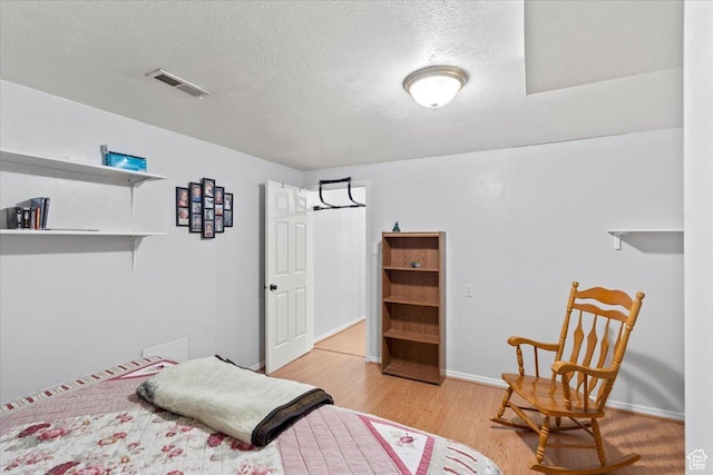 bedroom featuring light wood-style floors, a textured ceiling, and baseboards