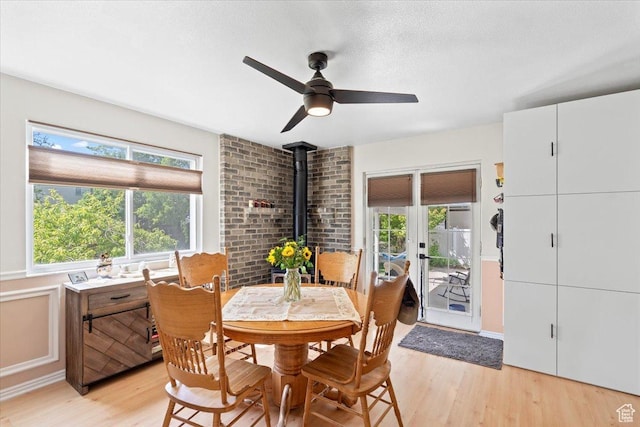 dining room featuring a wood stove, light wood-style floors, and a ceiling fan