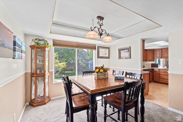 dining space featuring baseboards, light colored carpet, and a chandelier