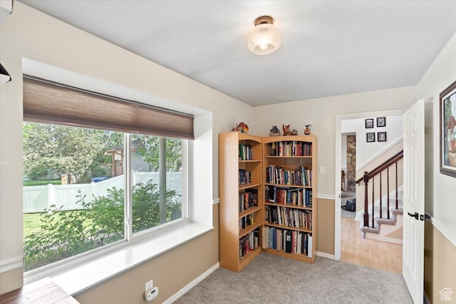 living area with stairway, carpet floors, baseboards, and a textured ceiling