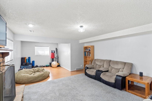living room featuring wood finished floors, a textured ceiling, and a fireplace
