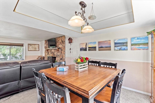 dining room featuring light colored carpet, a fireplace, and baseboards
