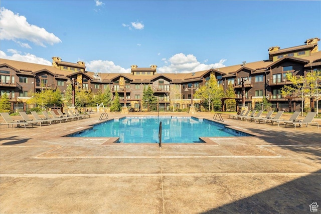 community pool with a residential view and a patio area