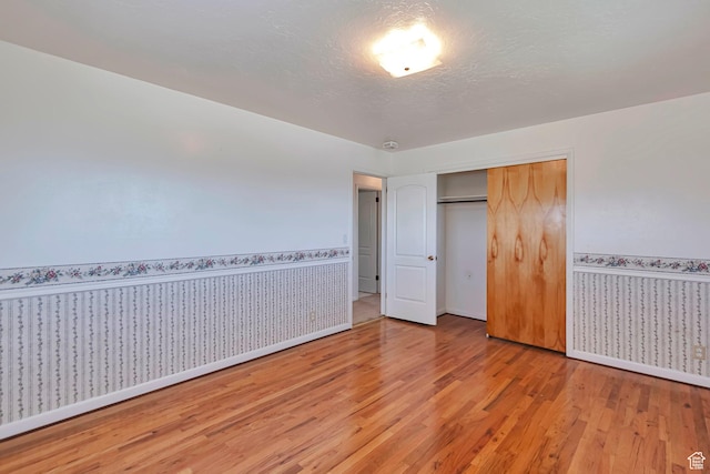 274 N 400 E, Hyde Park, UT 84318 - unfurnished bedroom with light wood finished floors, baseboards, a wainscoted wall, a closet, and wallpapered walls