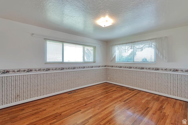 274 N 400 E, Hyde Park, UT 84318 - unfurnished room with light wood-type flooring, wainscoting, baseboards, a textured ceiling, and wallpapered walls