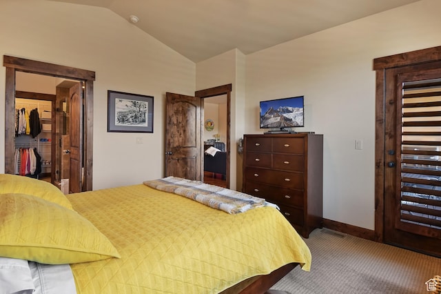 bedroom featuring carpet flooring, vaulted ceiling, a walk in closet, a closet, and baseboards