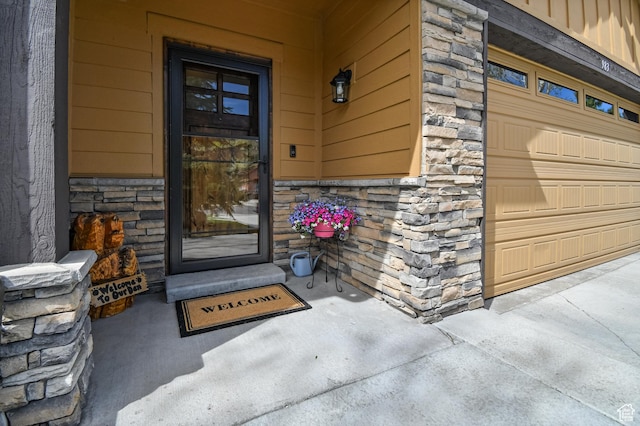 view of exterior entry featuring stone siding, a garage, and a porch