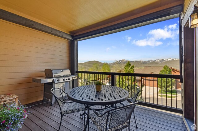 wooden deck with a mountain view, grilling area, and outdoor dining space