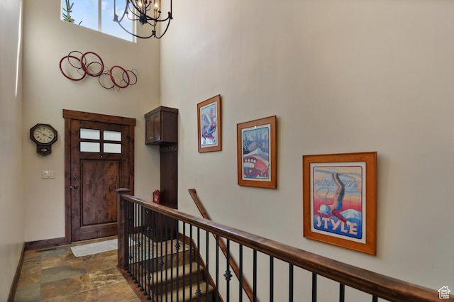 entrance foyer with a chandelier, stone finish floors, and a towering ceiling