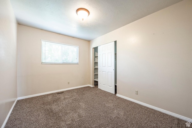 unfurnished bedroom featuring carpet floors, baseboards, a closet, and a textured ceiling