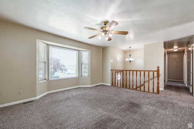 spare room featuring carpet floors, a ceiling fan, baseboards, a textured ceiling, and a chandelier