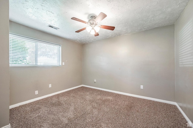 carpeted spare room featuring a textured ceiling, ceiling fan, and baseboards