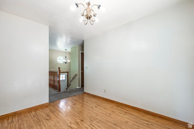 unfurnished room featuring a chandelier, light wood-type flooring, and baseboards