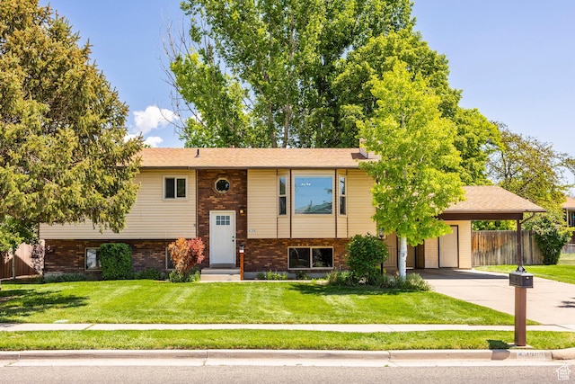 bi-level home with driveway, brick siding, and an attached carport