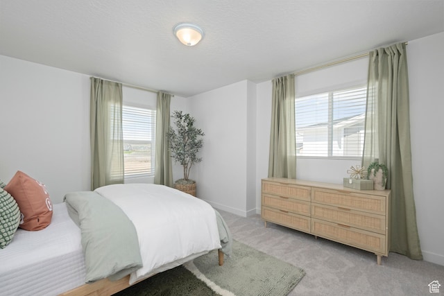 bedroom featuring multiple windows, light colored carpet, and baseboards