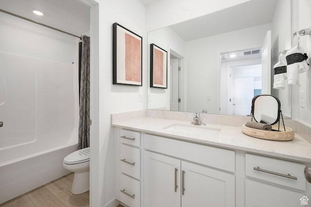 bathroom featuring toilet, vanity, wood finished floors, and shower / tub combo