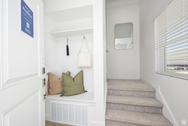 stairway featuring baseboards and carpet flooring