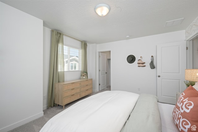 bedroom featuring light colored carpet, a textured ceiling, and baseboards