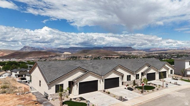 ranch-style house with concrete driveway, a garage, a mountain view, and stucco siding