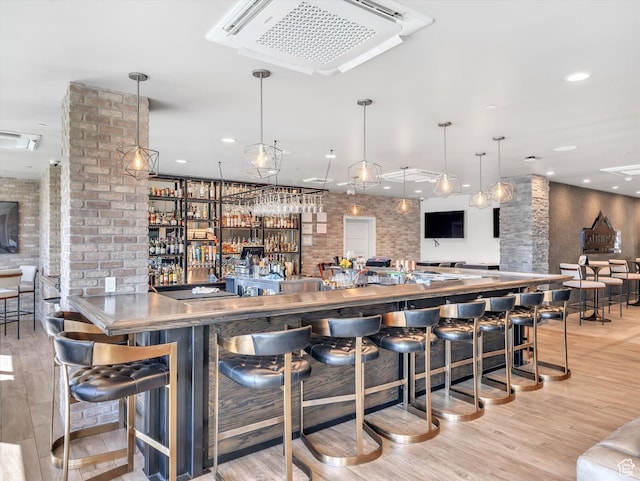indoor wet bar featuring light wood-style floors and decorative columns