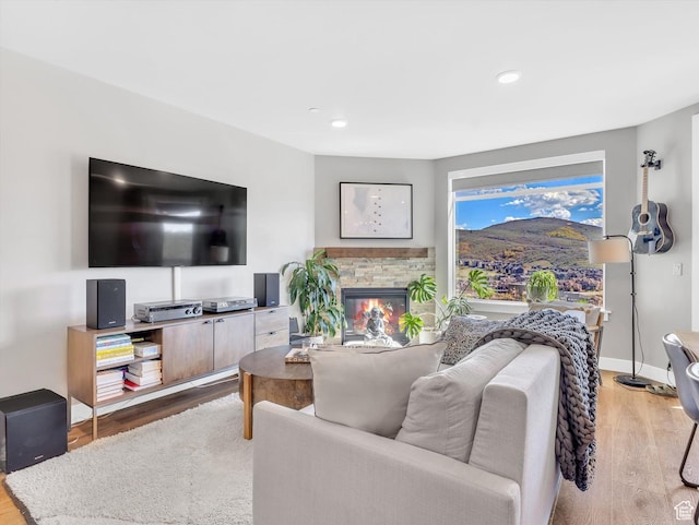 living room with wood finished floors, a fireplace, recessed lighting, and baseboards