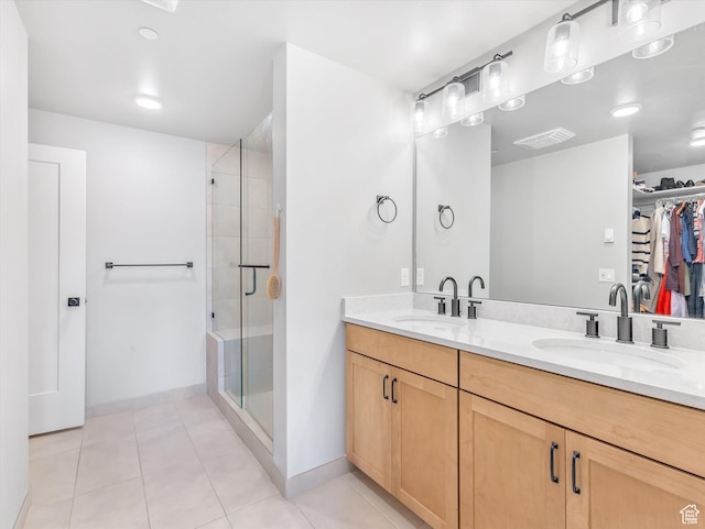 full bath featuring a walk in closet, baseboards, a stall shower, tile patterned flooring, and double vanity