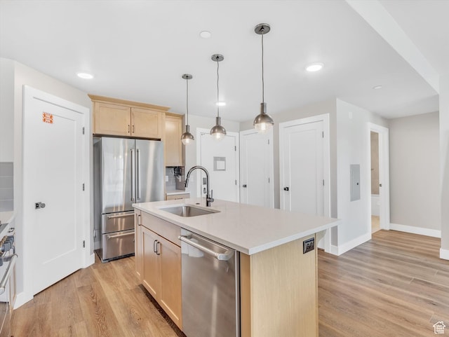 kitchen featuring stainless steel appliances, light brown cabinetry, a sink, light wood-style floors, and light countertops