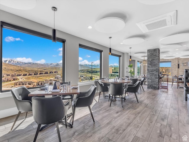 dining area with wood finished floors, healthy amount of natural light, a mountain view, and recessed lighting