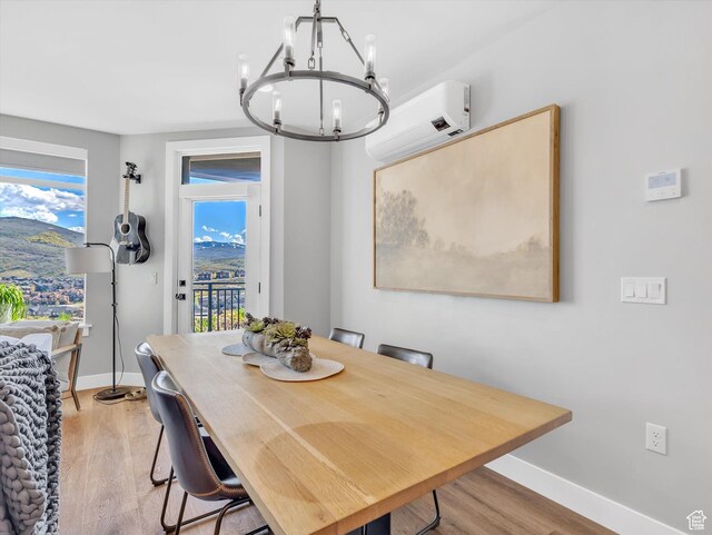 dining room featuring a wall mounted air conditioner, a chandelier, light wood finished floors, and baseboards