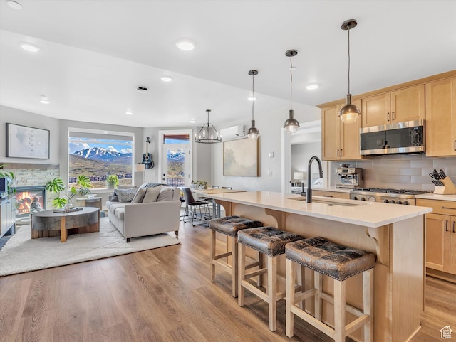 kitchen featuring stainless steel microwave, light brown cabinetry, a sink, light wood-type flooring, and light countertops
