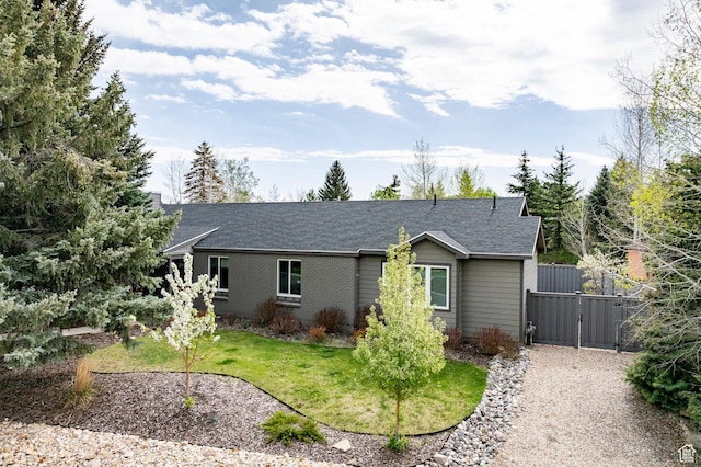 ranch-style home with a gate, a shingled roof, and a front yard