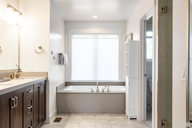 full bathroom with a garden tub, double vanity, toilet, baseboards, and tile patterned floors