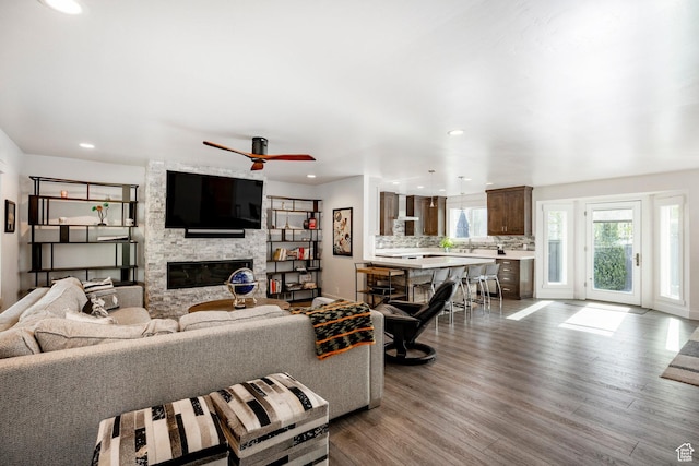 living area featuring a fireplace, wood finished floors, ceiling fan, recessed lighting, and baseboards