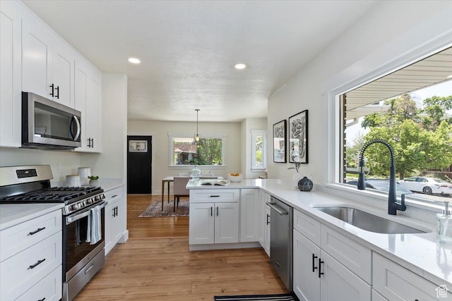 kitchen featuring stainless steel appliances, a sink, recessed lighting, light countertops, and white cabinetry
