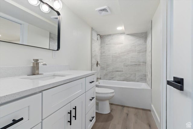bathroom with wood finished floors, toilet, vanity, shower / washtub combination, and recessed lighting