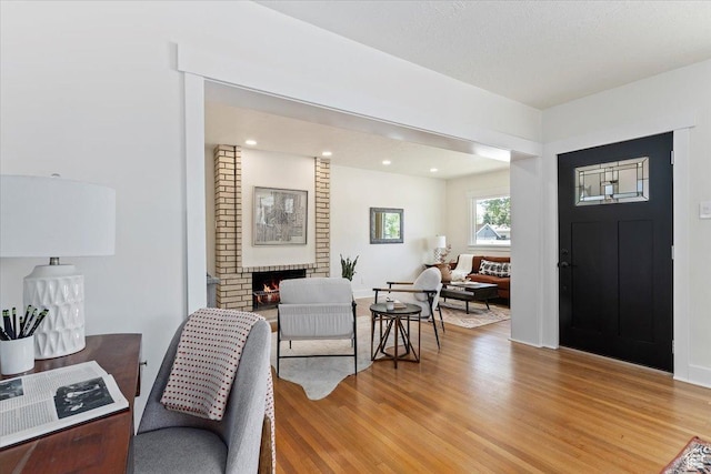 foyer entrance featuring light wood finished floors, a brick fireplace, and recessed lighting