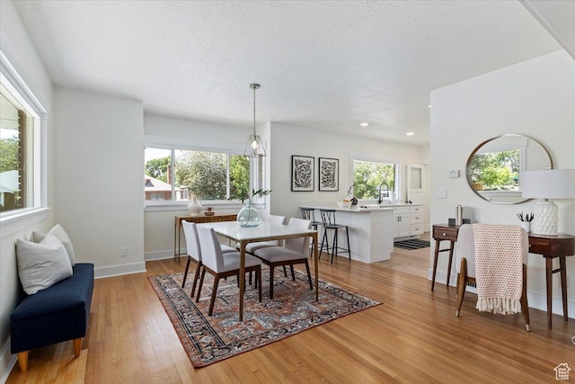 dining area with light wood-type flooring, baseboards, recessed lighting, and a textured ceiling