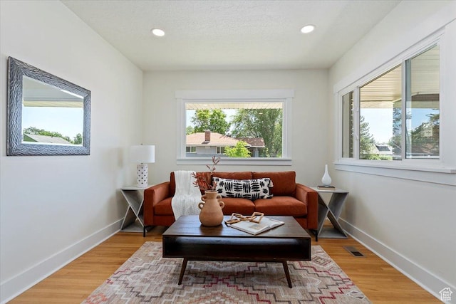living area featuring baseboards, recessed lighting, and light wood finished floors